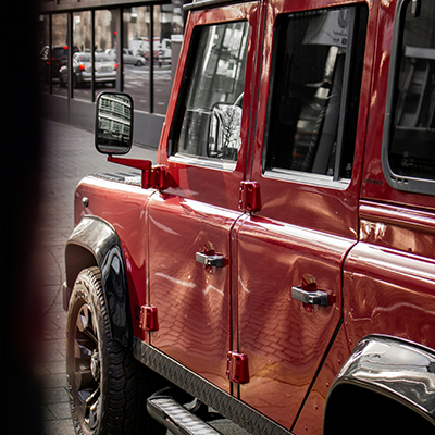 Red Land Rover Defender parked in an urban setting serviced by AJ 4X4 